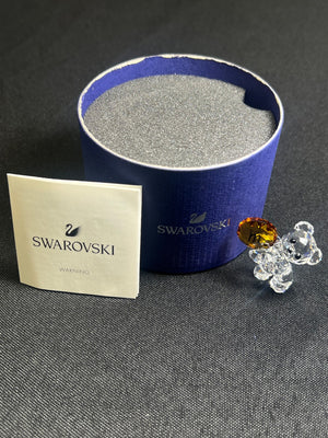 Swarovski crystal with packaging and a Swarovski branded card on a dark surface