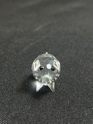 Clear crystal pig-shaped object on a dark textured fabric background