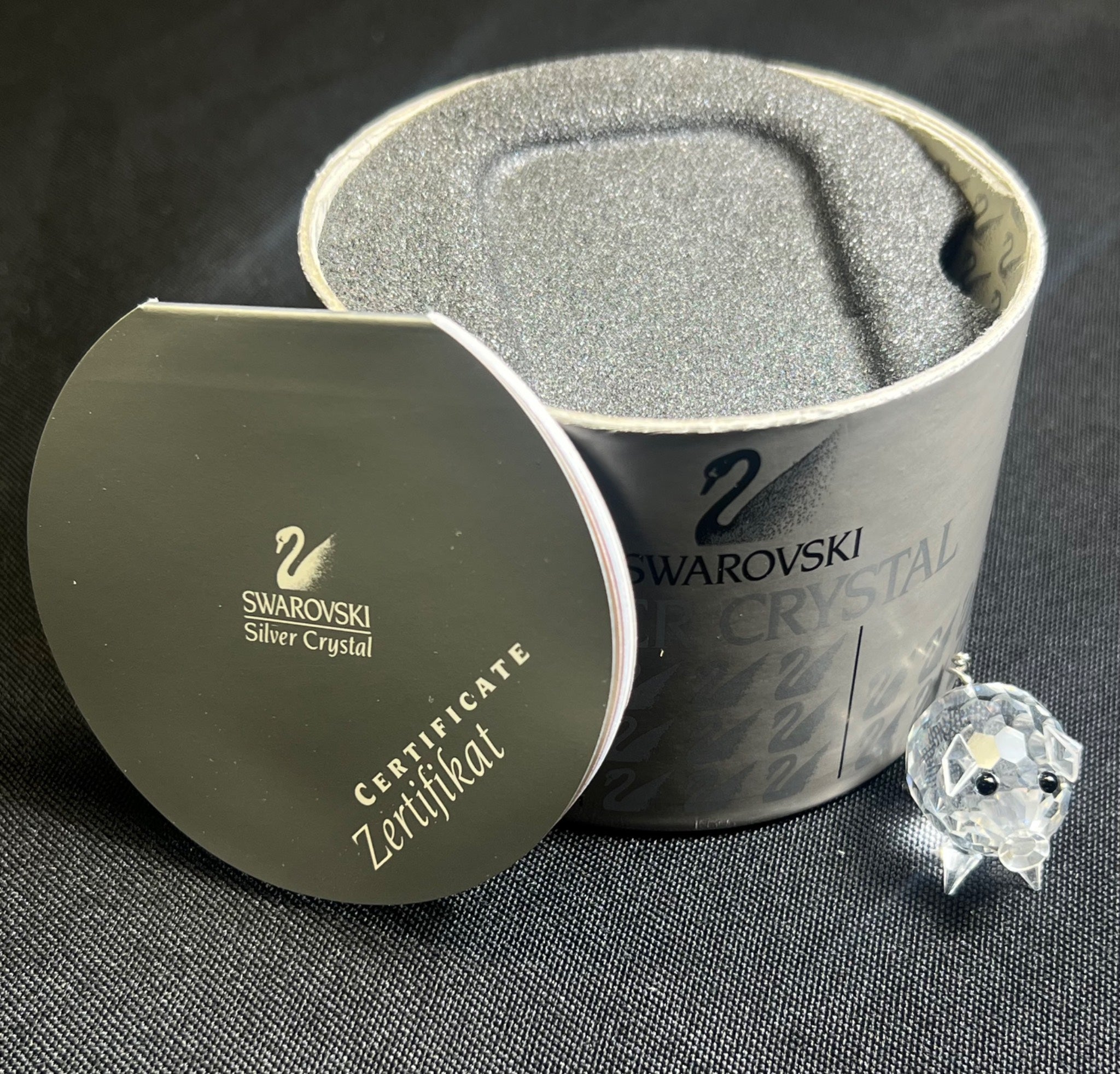 Swarovski crystal earring in a branded box on a dark background