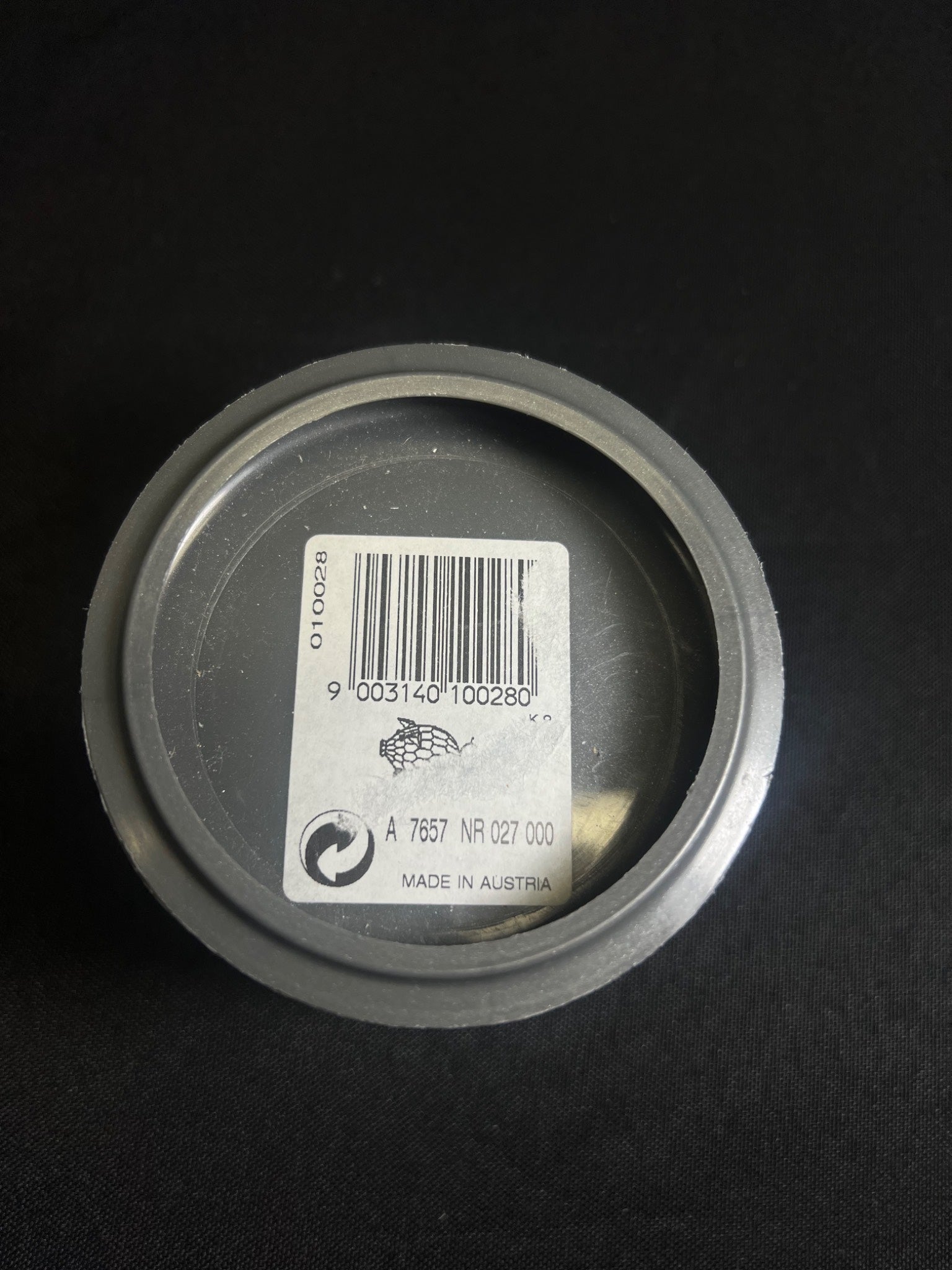 Metallic can lid with a barcode label on a black background