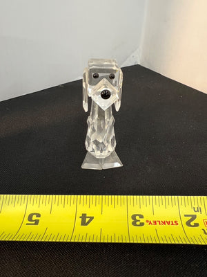 Clear glass dog figurine on a black surface with a measuring tape for scale.