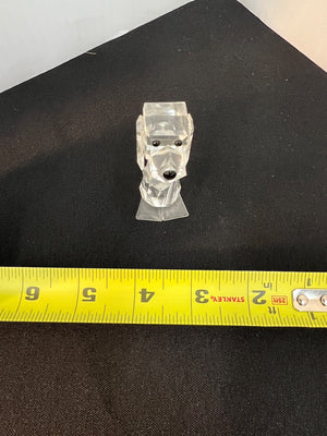 Clear plastic dog-shaped object on a black surface with a yellow measuring tape for scale.