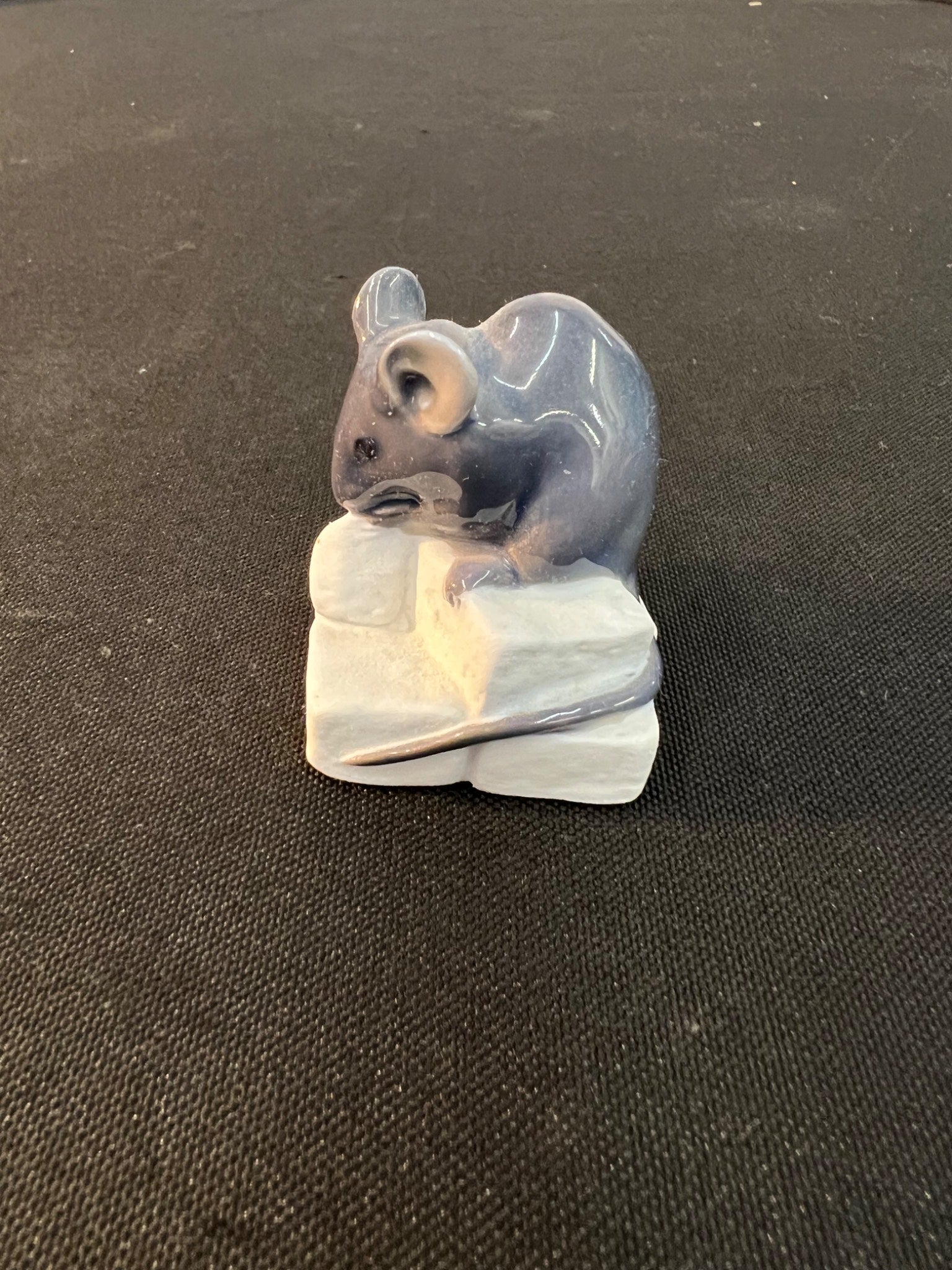 Small ceramic mouse figurine on a black background