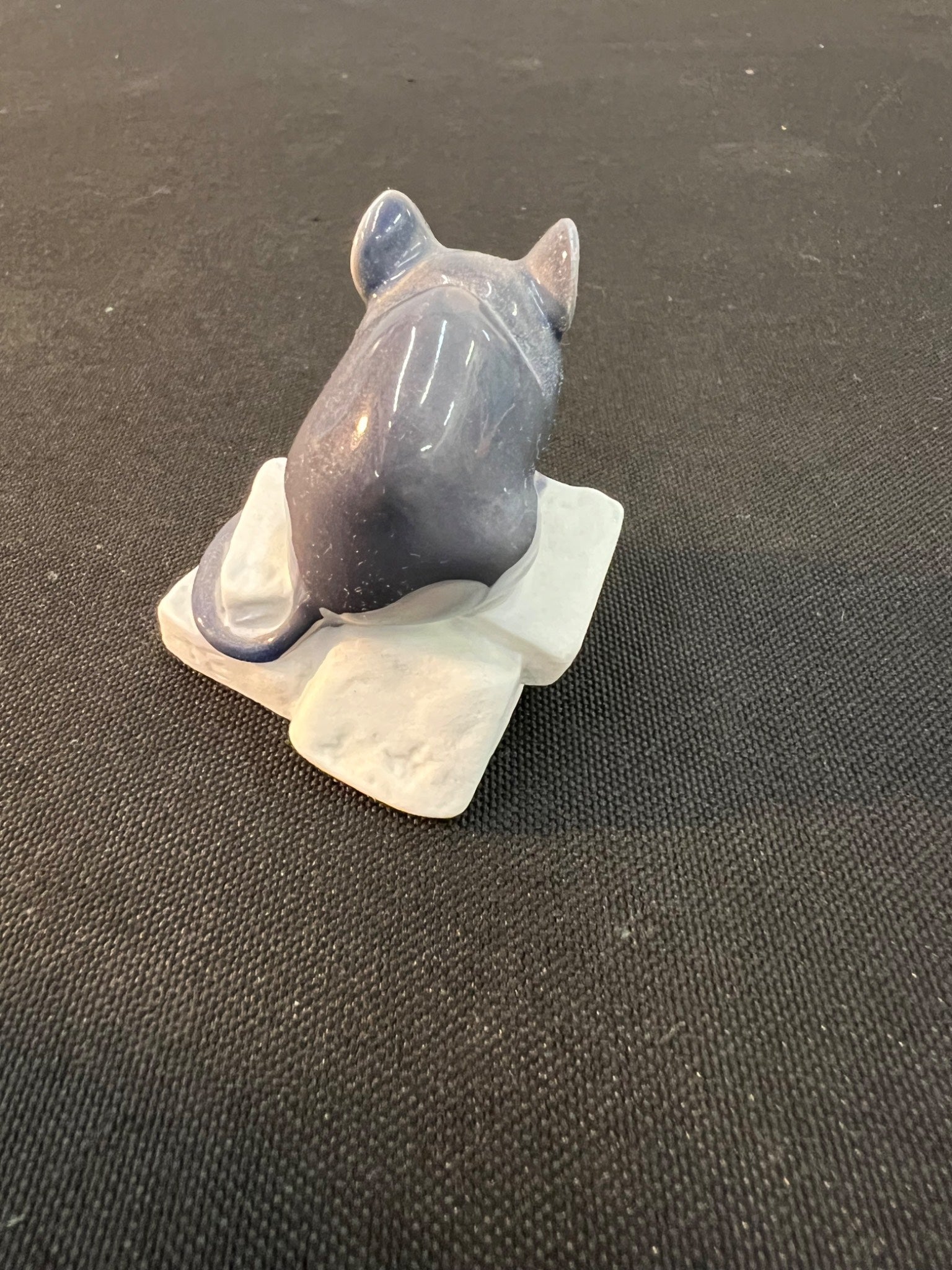 Small figurine of a cat on a textured black surface