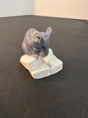 Small mouse figurine on a white base against a dark background