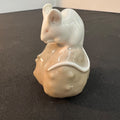 Ceramic mouse figurine with a shell on a dark surface