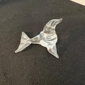 Clear glass dolphin figurine on a dark surface