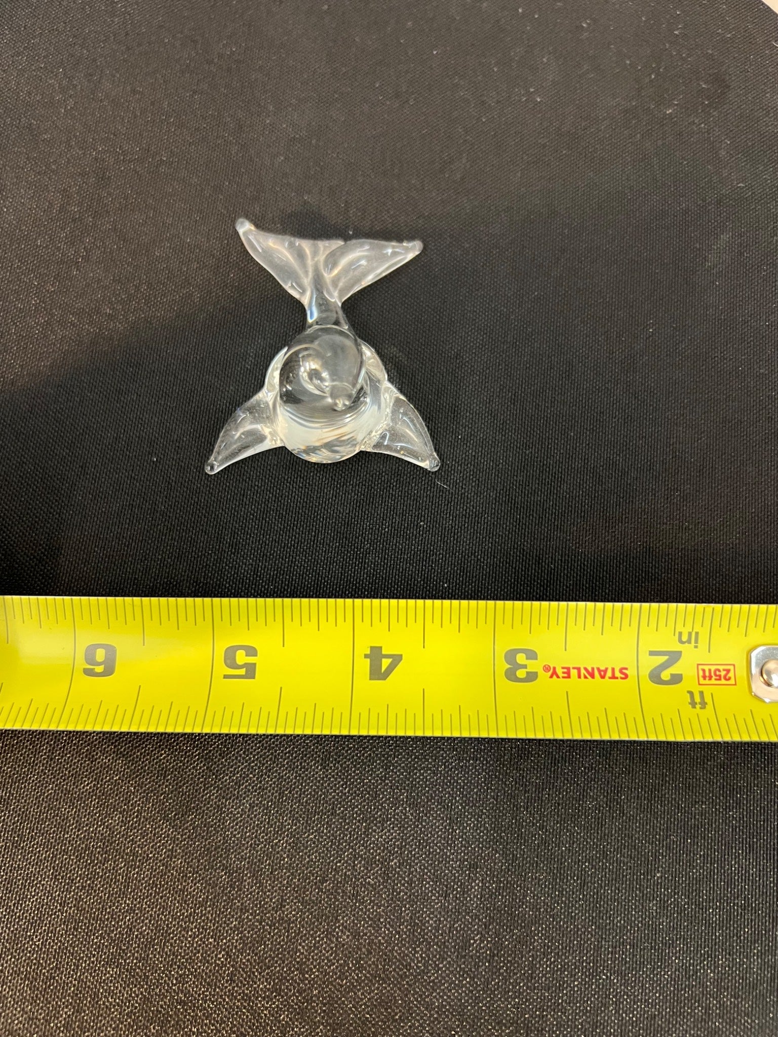 Metallic trident-shaped object on a black background with a yellow measuring tape for scale.