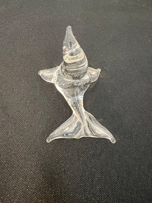 Glass sculpture of a fish on a dark fabric background