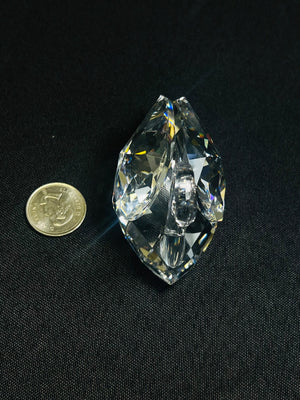 Teardrop-shaped crystal next to a coin on a black background
