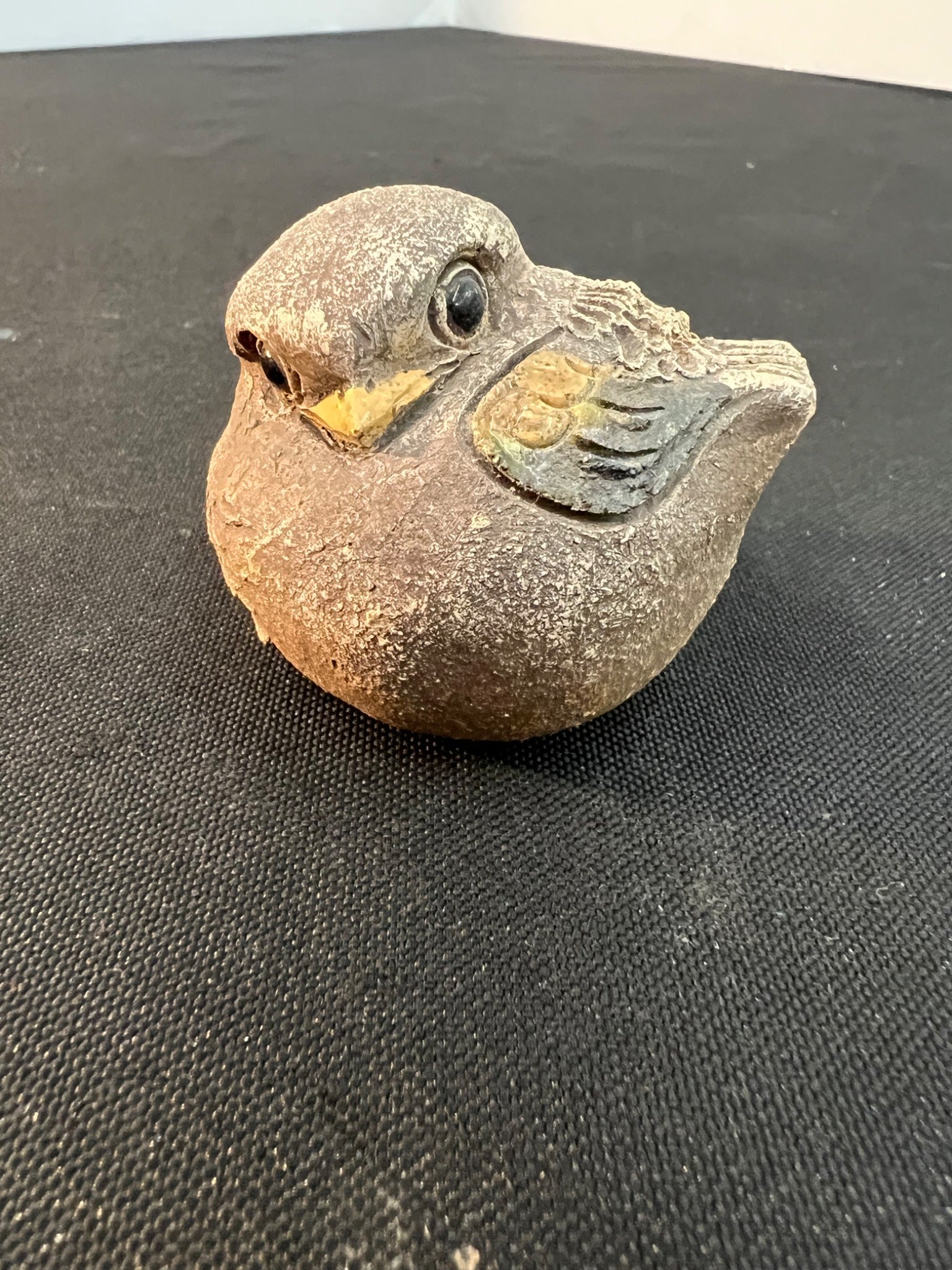 Stone sculpture of a bird on a black surface