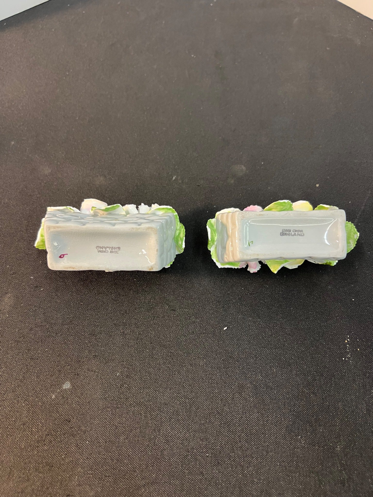 Two decorative items with green bases on a black surface