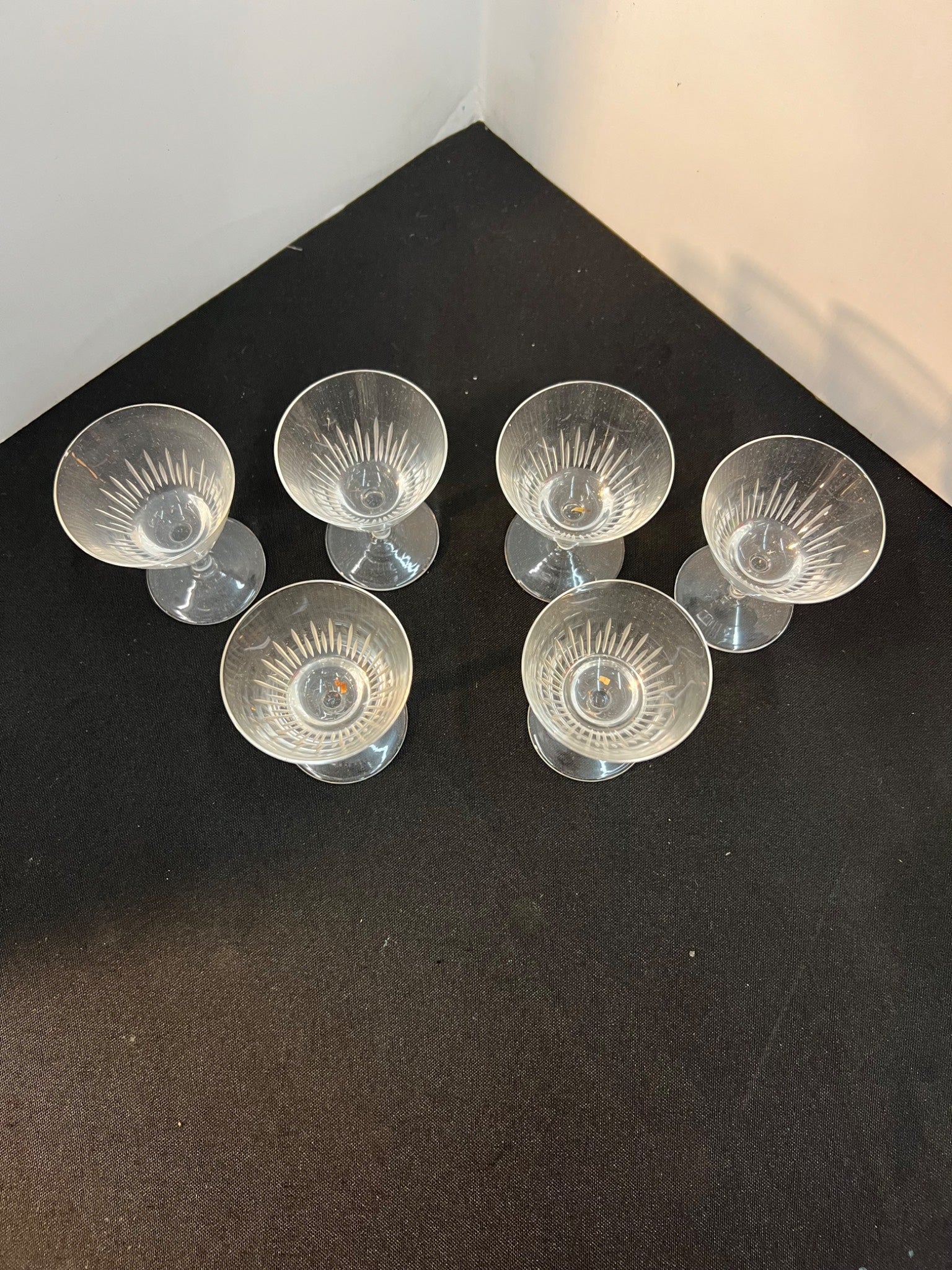 Set of six clear glass candle holders on a black surface.