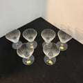 Set of six clear glass cocktail glasses on a black surface with a white background