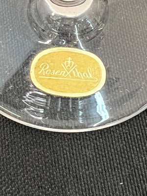 Clear glass object with a gold label featuring 'Rosenfeld' on a textured gray background