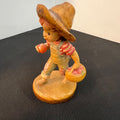 Vintage figurine of a child in a straw hat holding a basket on a black surface.