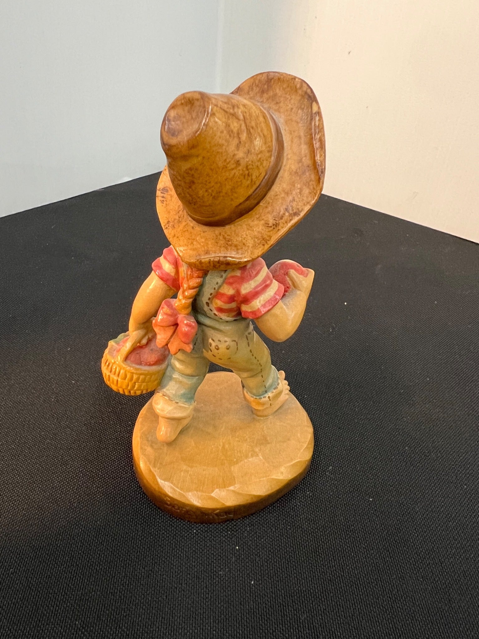 Wooden figurine of a cowboy with a hat and boots on a black surface