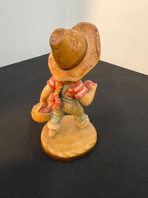 Wooden figurine of a cowboy with a hat and boots on a black surface