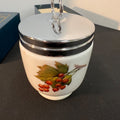 Decorative ceramic jar with a silver lid on a dark surface