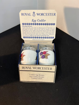 Two Royal Worcester egg coddlers in packaging on a dark surface.