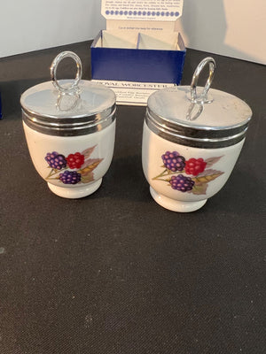 Two small ceramic jars with floral designs on a dark surface.