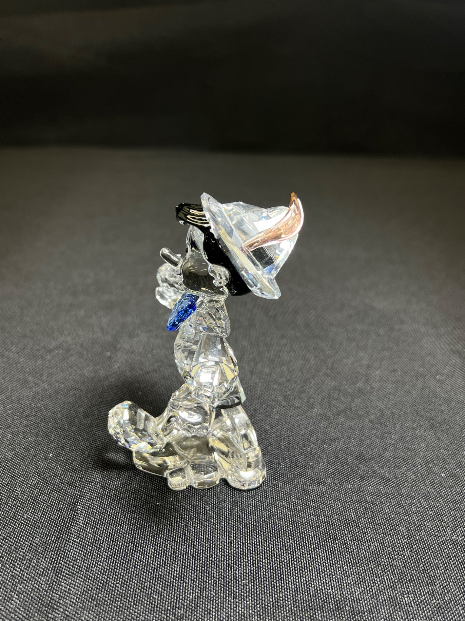 Crystal dog figurine with a black hat on a gray background