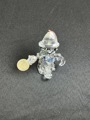Small transparent figurine with a coin for scale on a gray background