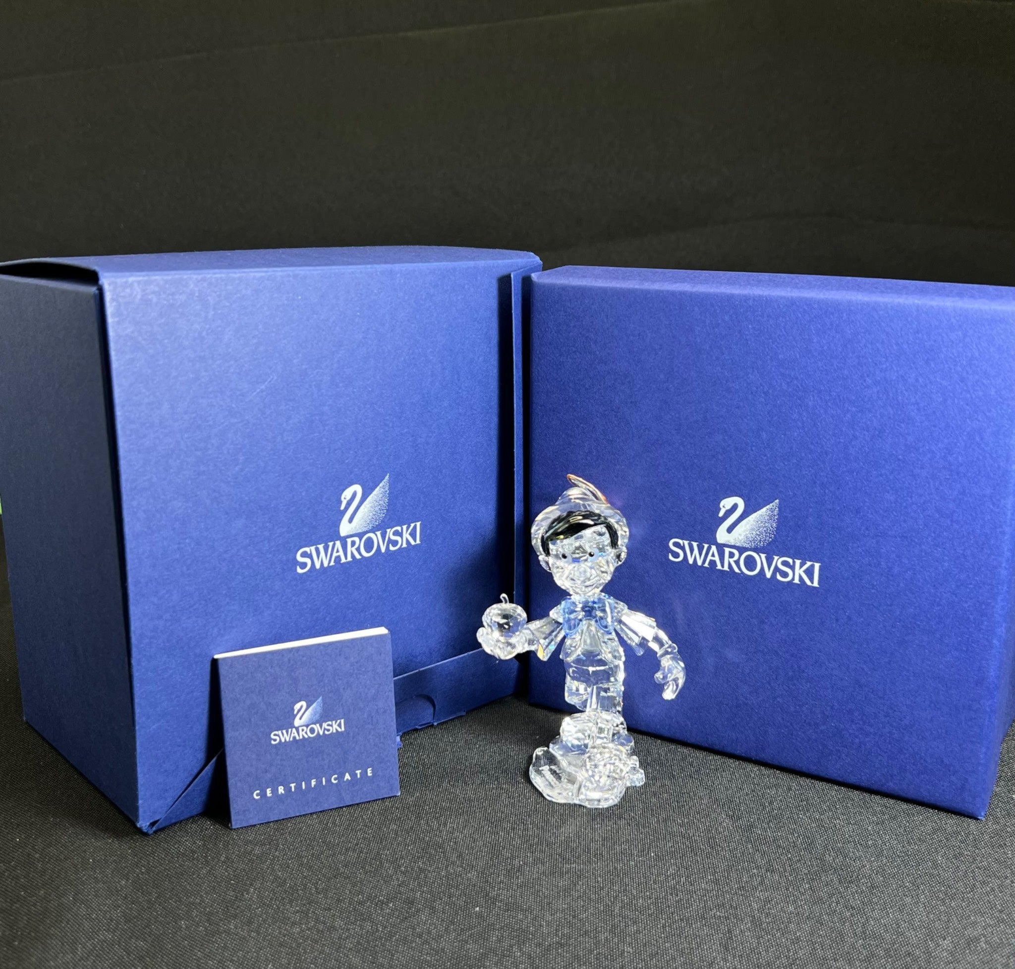Swarovski crystal figurine with blue packaging and certificate on a dark background