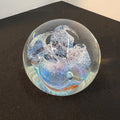 Glass paperweight with abstract design on a black surface