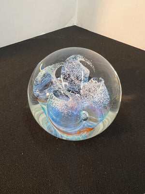 Glass paperweight with abstract design on a black surface