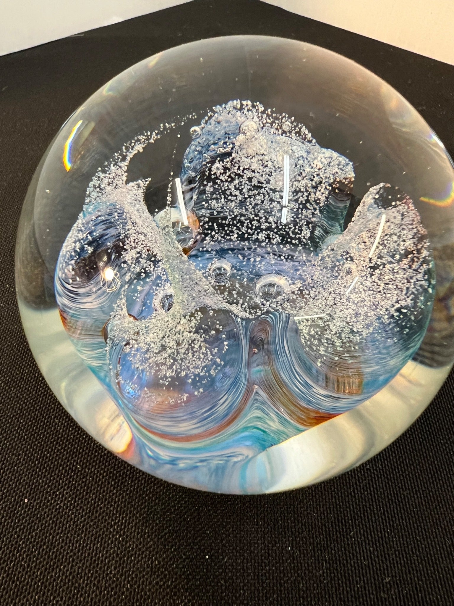 Glass paperweight with ice-like texture on a black background