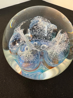 Glass paperweight with ice-like texture on a black background