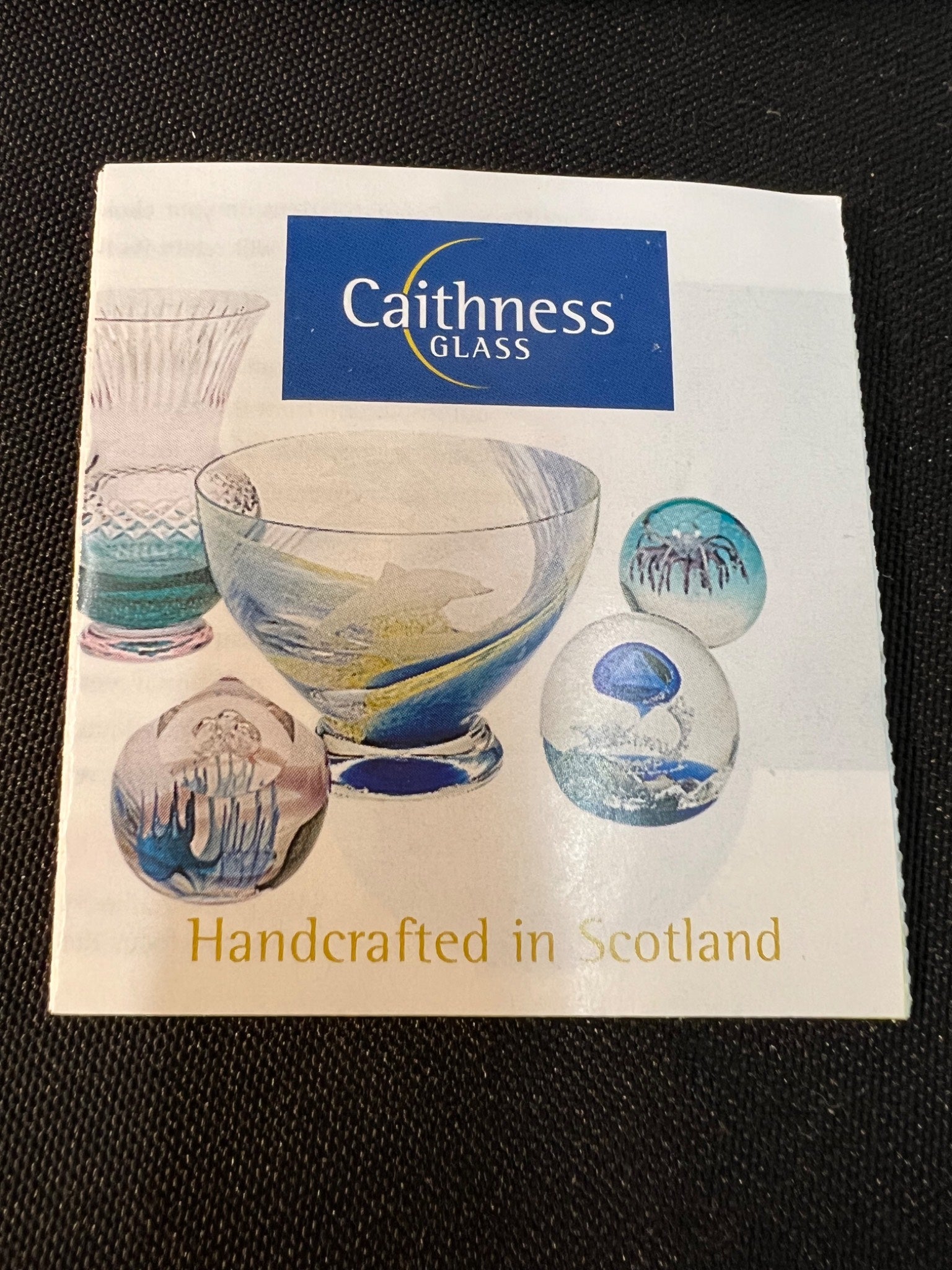 Caithness Glass promotional material with glass pieces on a black background