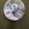 Decorative glass paperweight with intricate designs on a dark surface