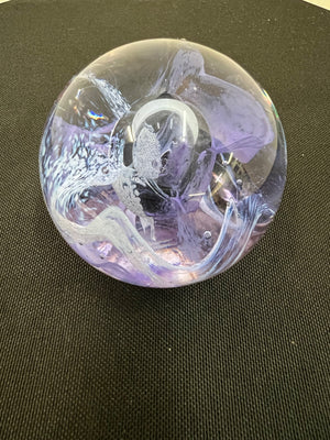 Decorative glass paperweight with intricate designs on a dark surface