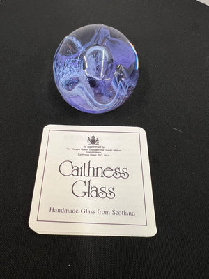 Purple glass paperweight with Caithness Glass label on a black background