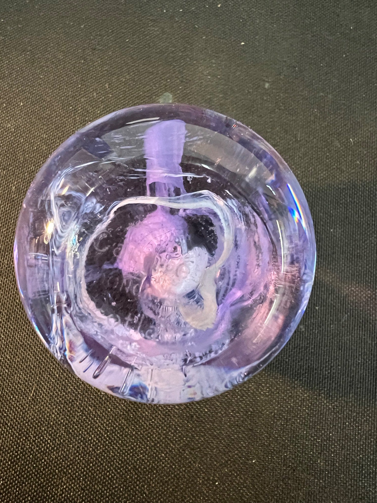Clear glass object with a pink and white interior on a dark surface