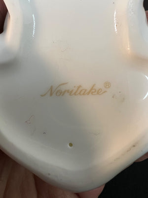 Close-up of a white ceramic item with 'Noritake' branding in gold.