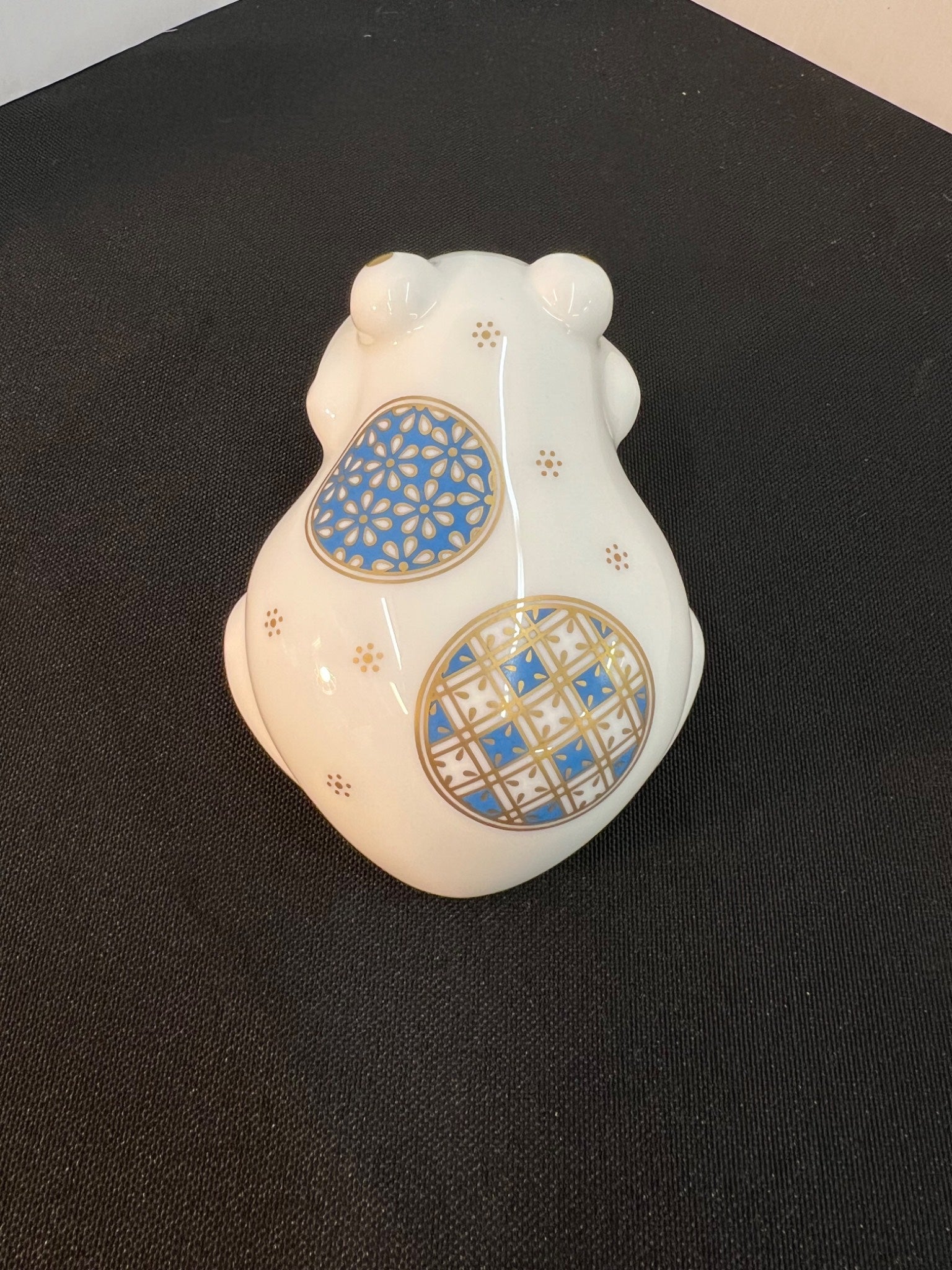 Decorative ceramic bear figurine with blue and gold patterns on a black background