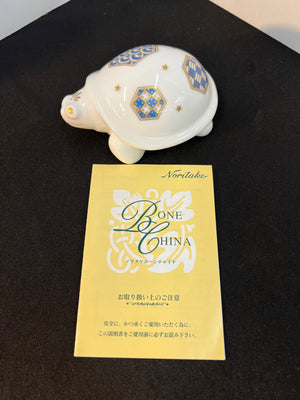 Decorative shell with intricate patterns on a black surface, accompanied by a Bone China card.