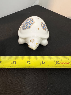 Decorative turtle figurine with geometric patterns on a black surface with a measuring tape.