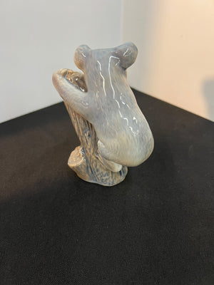 Ceramic bear figurine on a black surface with a neutral background