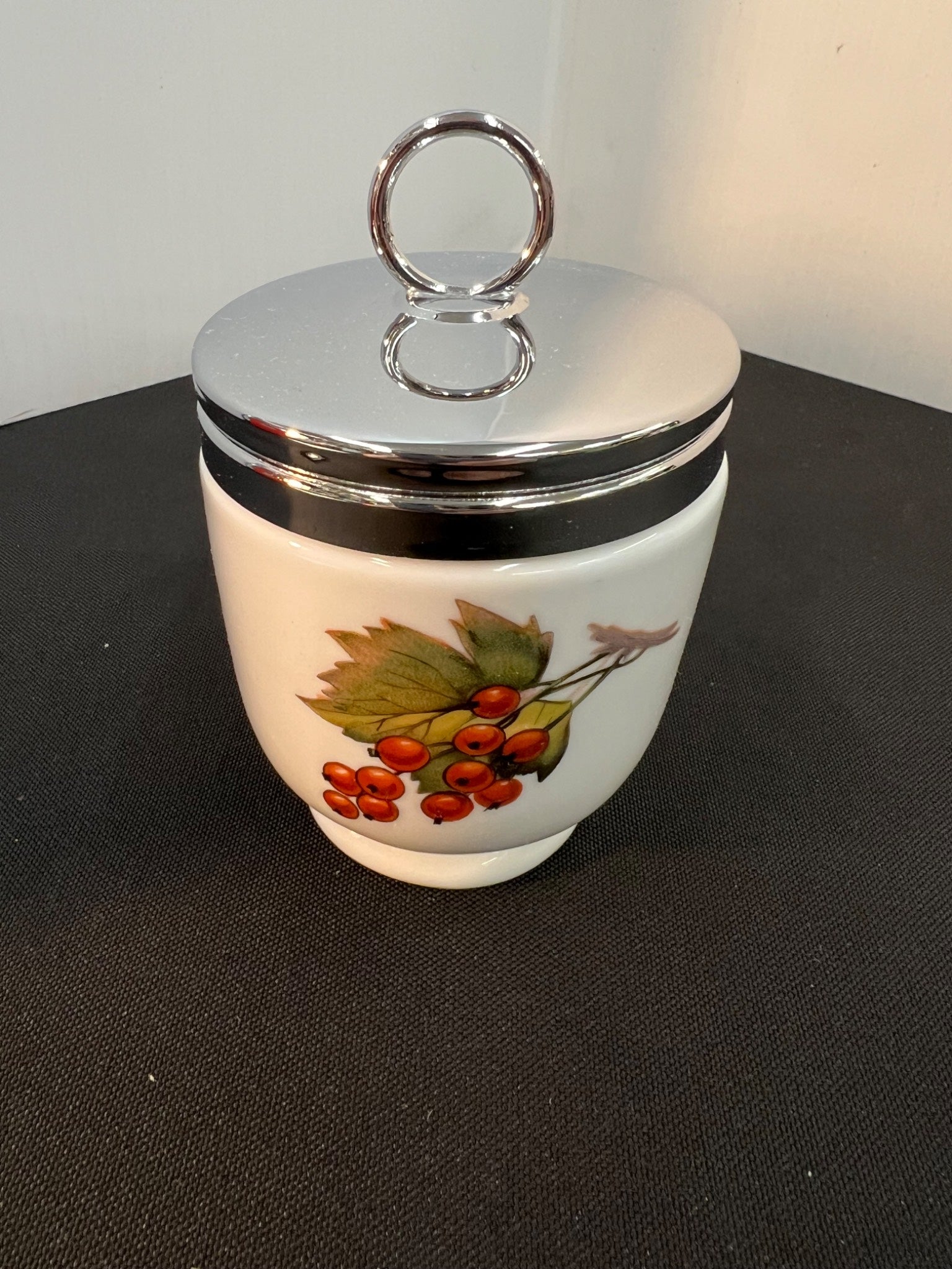 Decorative ceramic jar with a silver lid on a black surface