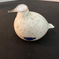 White ceramic duck figurine with a blue label on a black surface