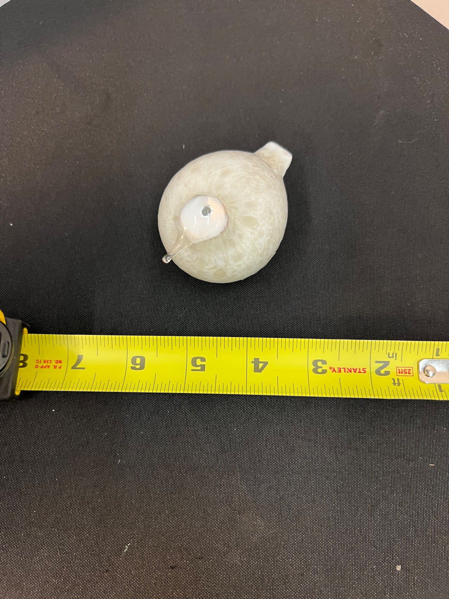 White spherical object on a black surface with a yellow measuring tape