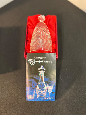 Crystal decanter with a care guide on a black surface