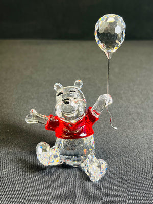 Crystal bear figurine with a red shirt and clear balloon on a dark background