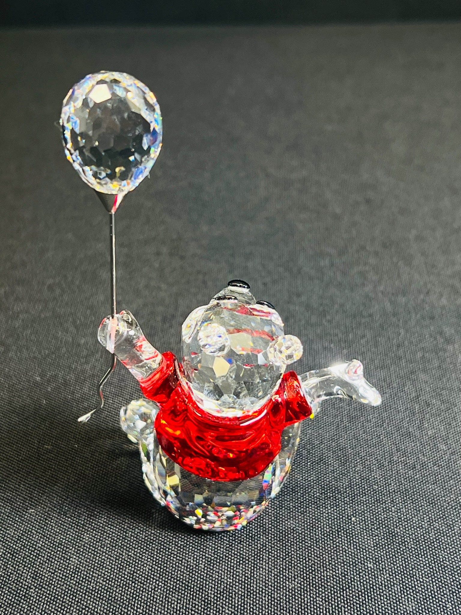 Crystal figure of a snowman with a balloon on a dark background