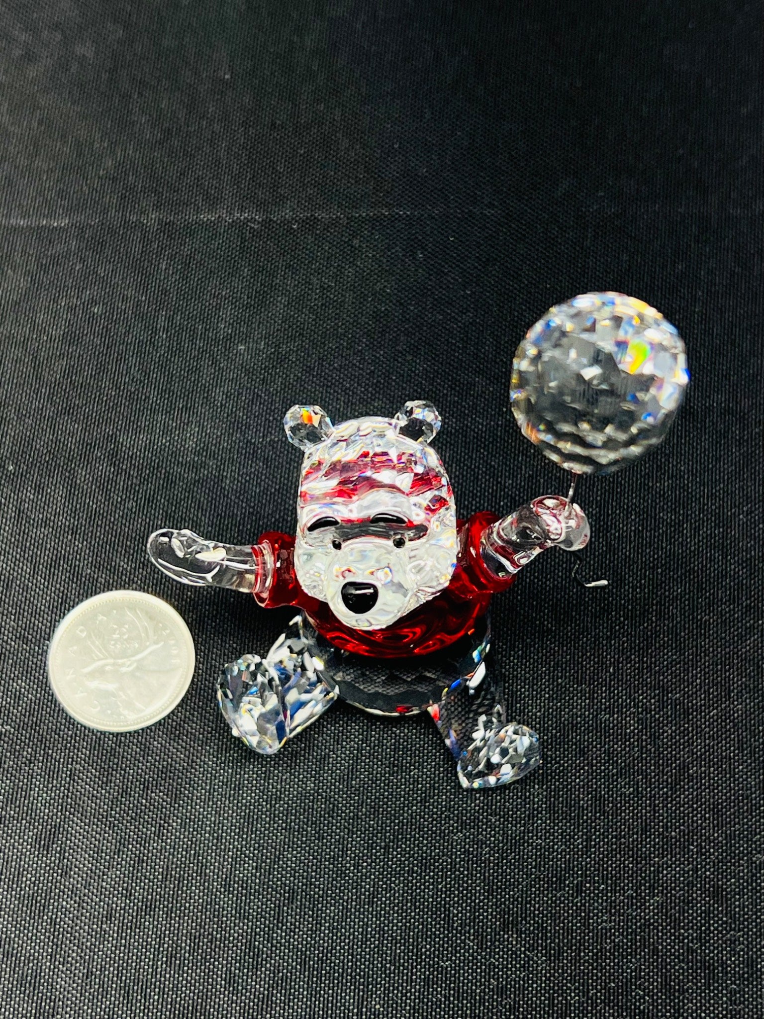 Glass bear figurine with red shirt and black pants on a dark background