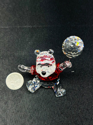 Glass bear figurine with red shirt and black pants on a dark background